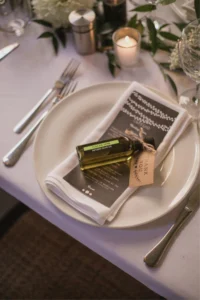 60ml olive oil favour bottle with Thank You tag on a white wedding dinner plate
