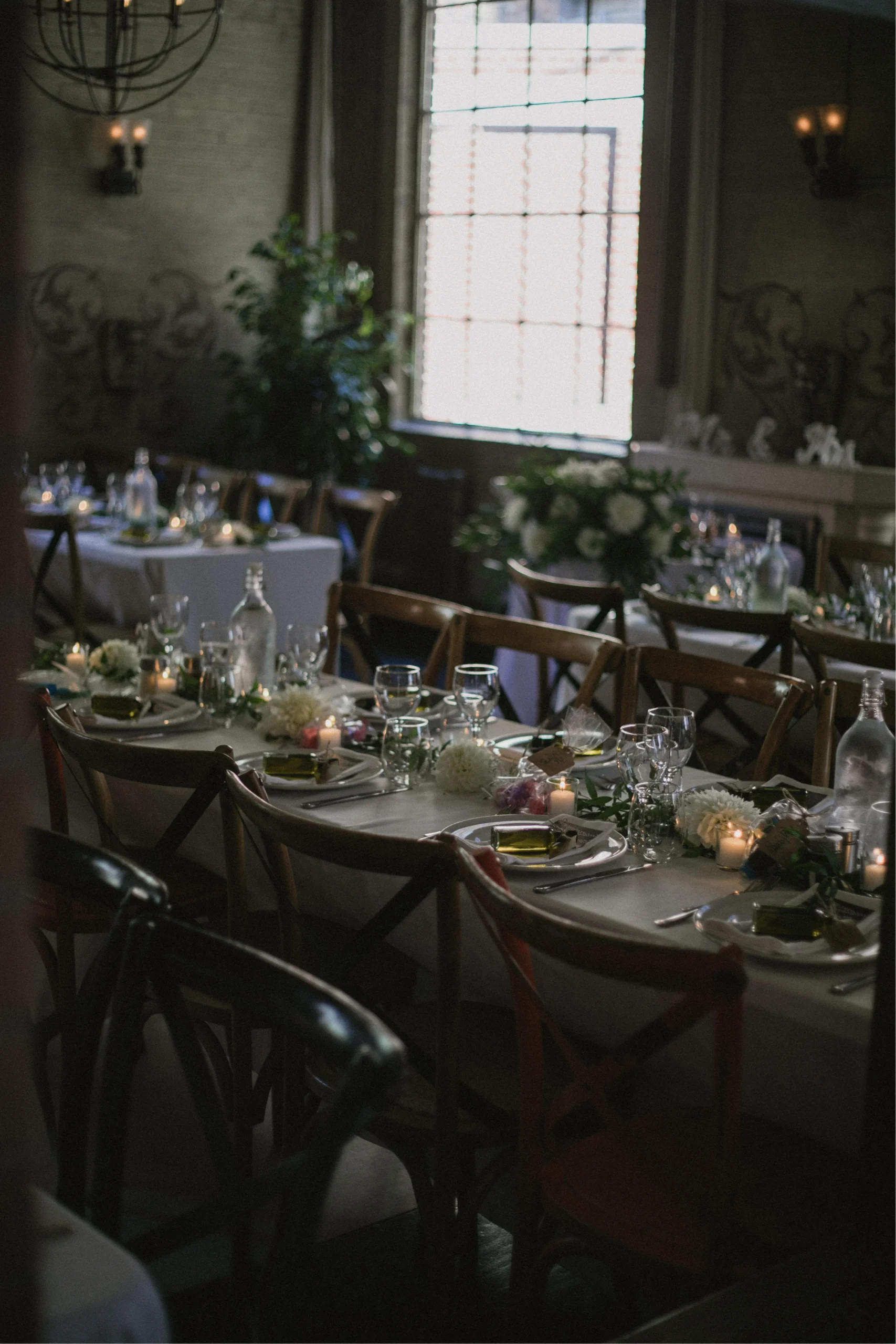 Long wedding reception table with olive oil favours, white flowers, and candles