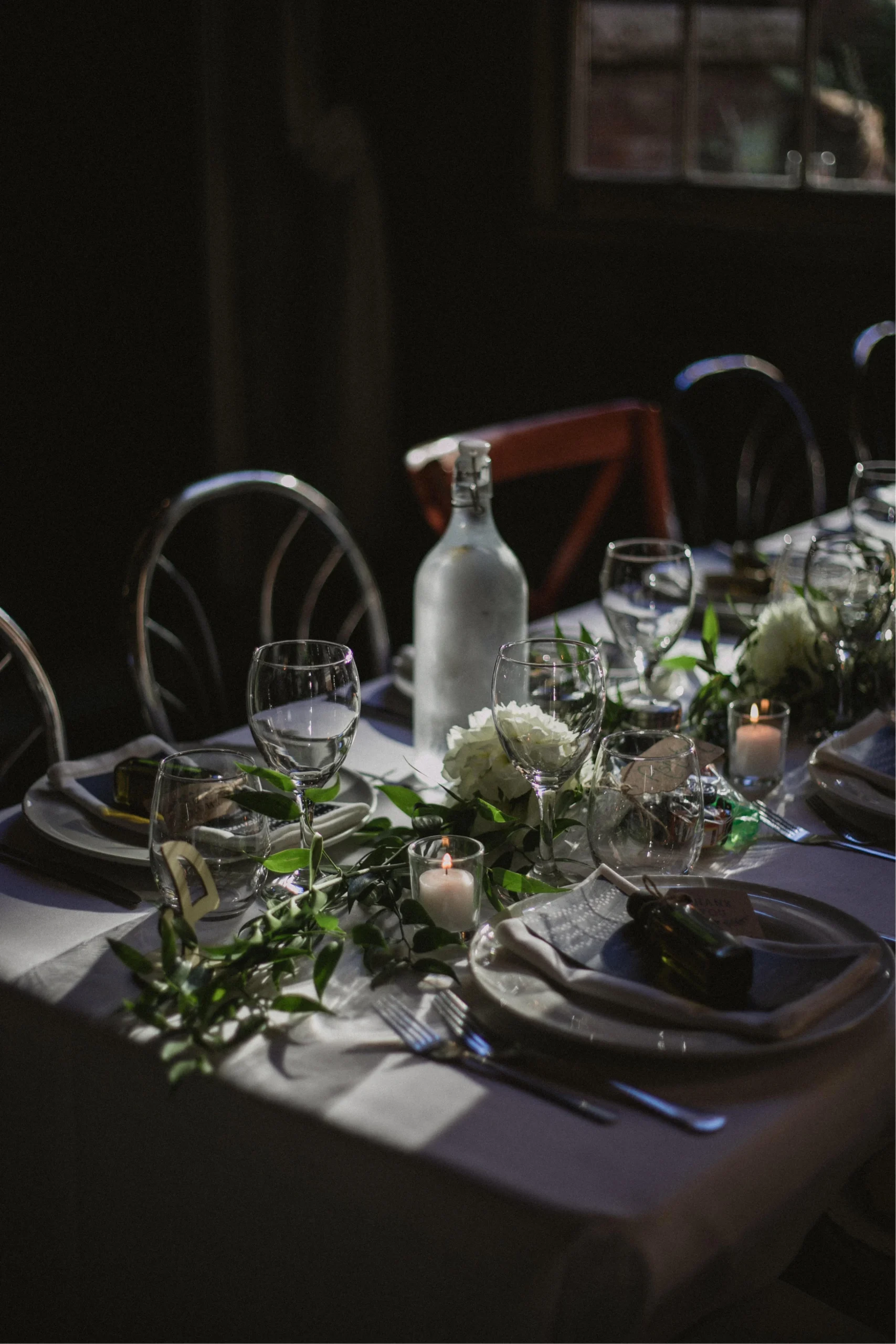 Elegant wedding dinner table with olive oil favours, glassware, and white floral arrangements