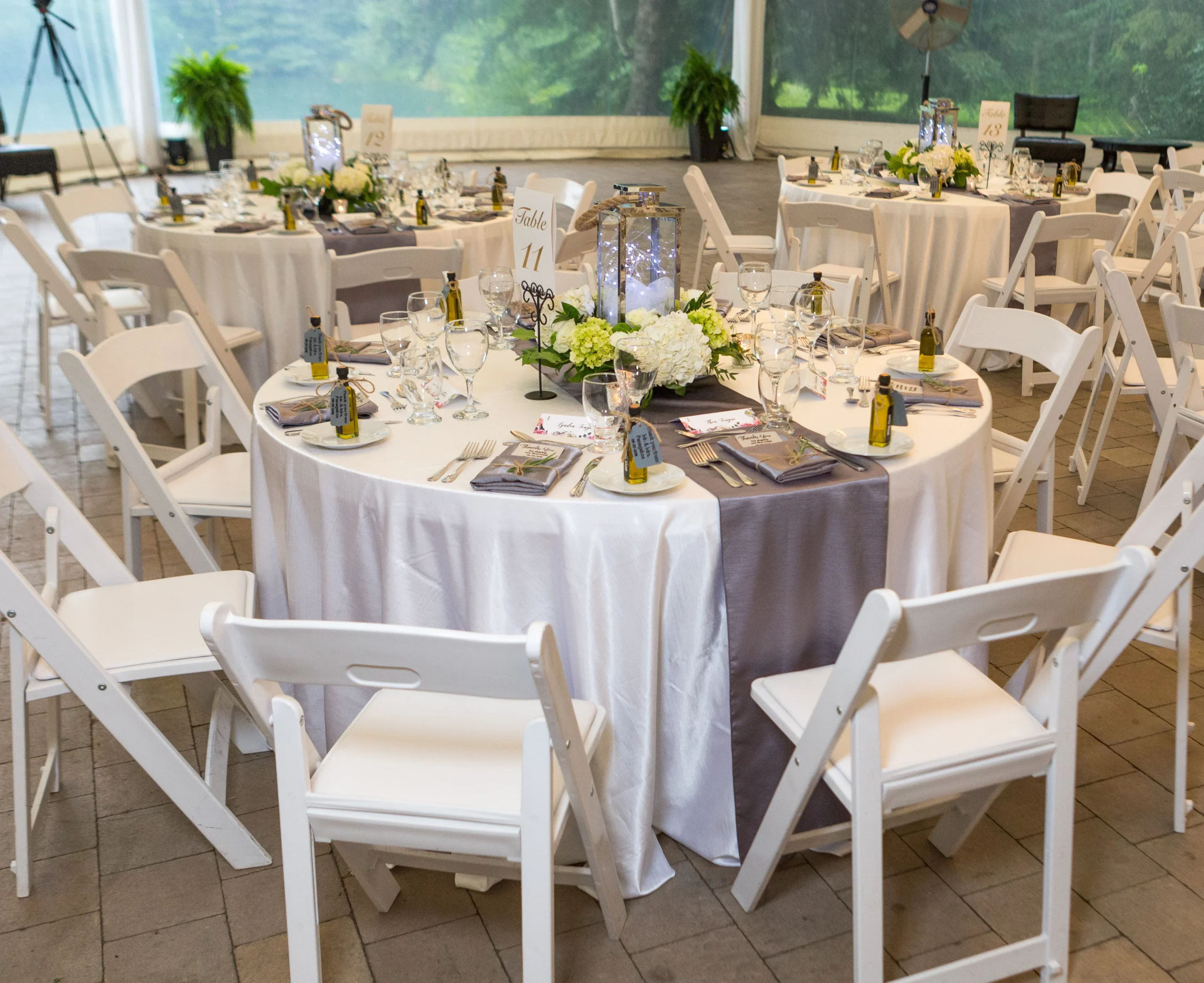 Wedding reception room with Olive That! olive oil favour bottles at every place setting