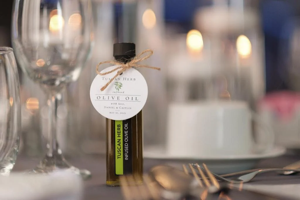 Single 60ml Tuscan Herb infused olive oil wedding favour with twine bow and custom tag at a candlelit place setting